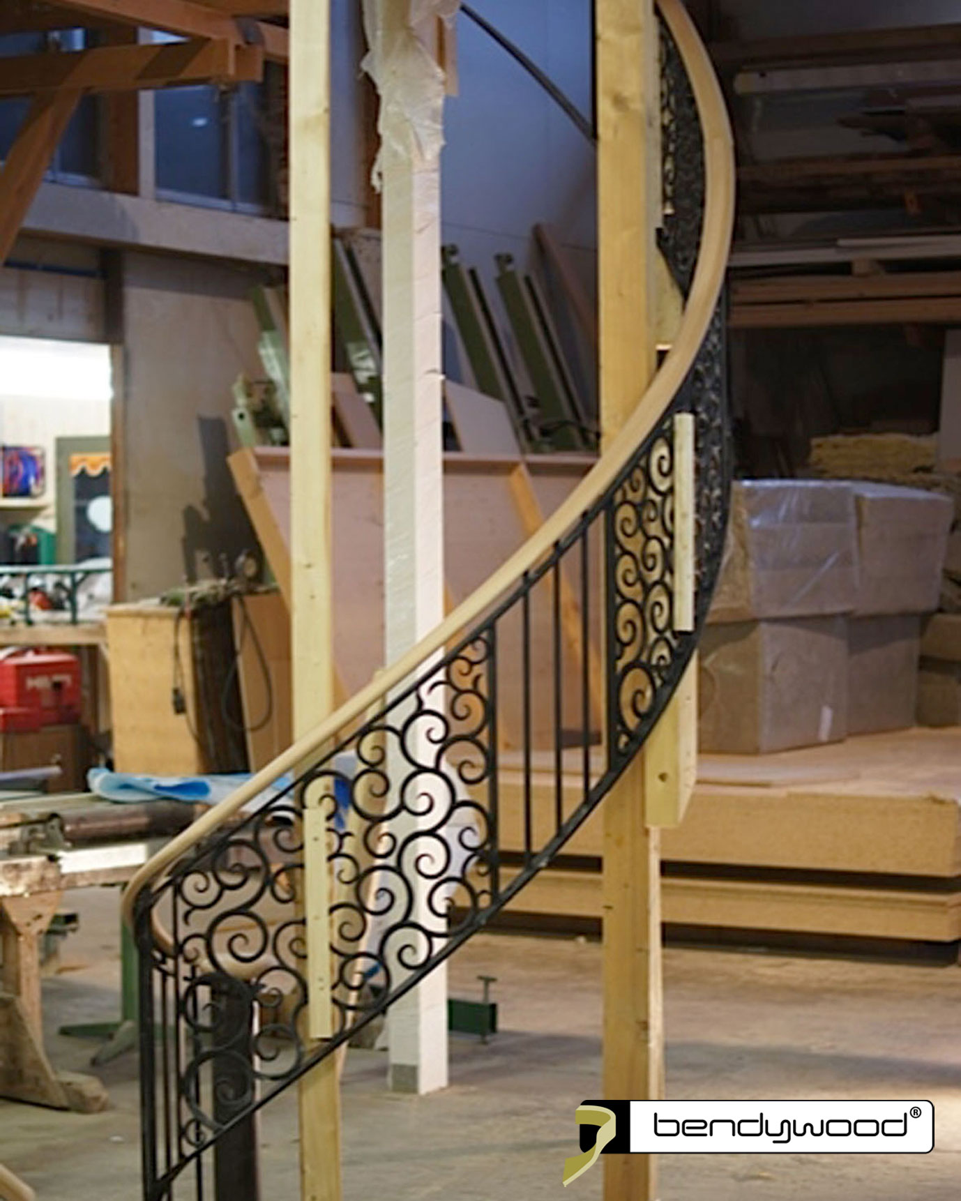 Corrimano ovale in faggio Bendywood® per una scala curva con balaustra in ferro battuto. 