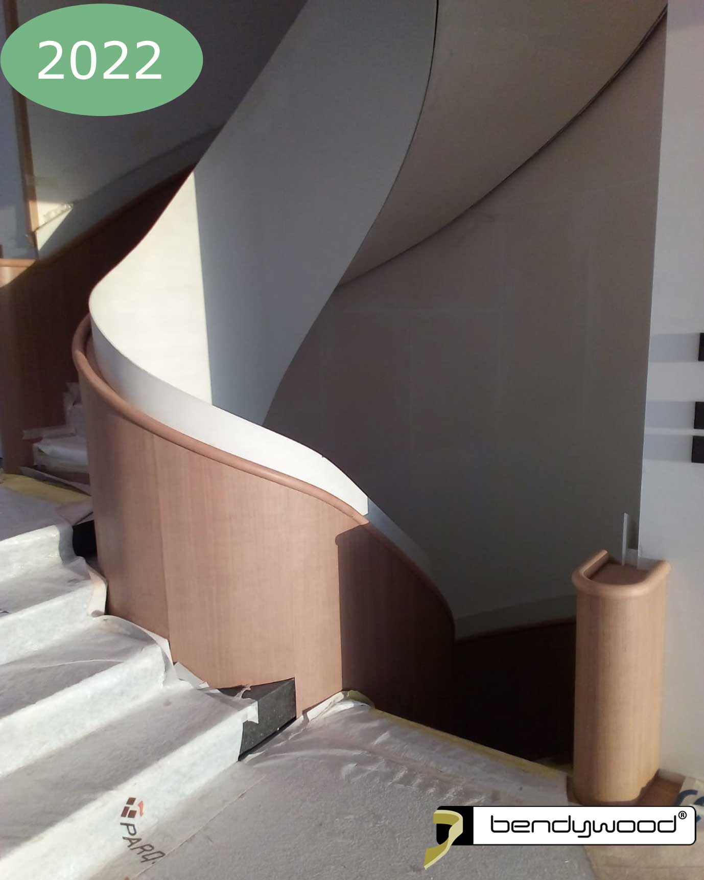 Corrimano rotondo Bendywood® su rivestimento in legno di una scala in acciaio.