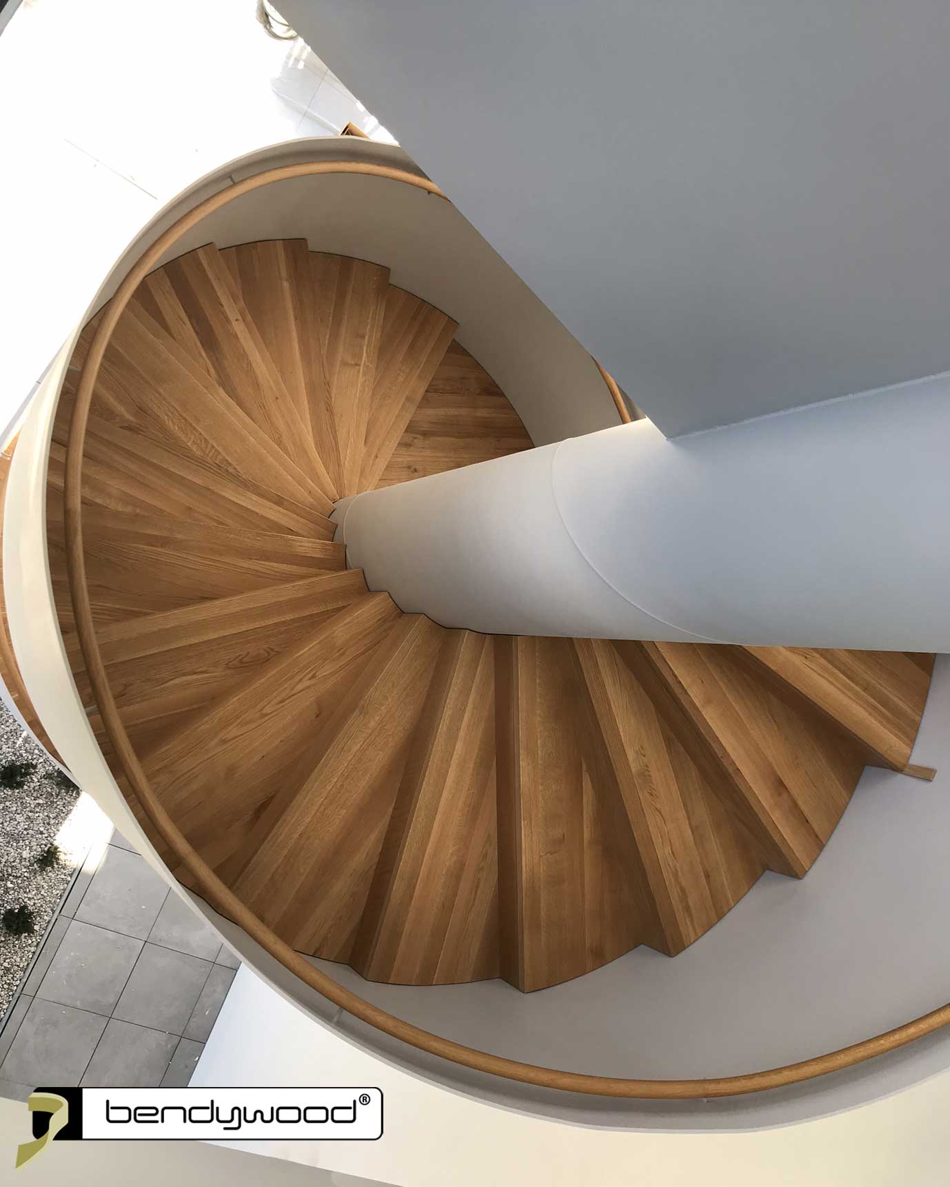 Scala a chiocciola design con paratia laterale in acciaio e corrimano in rovere Bendywood®